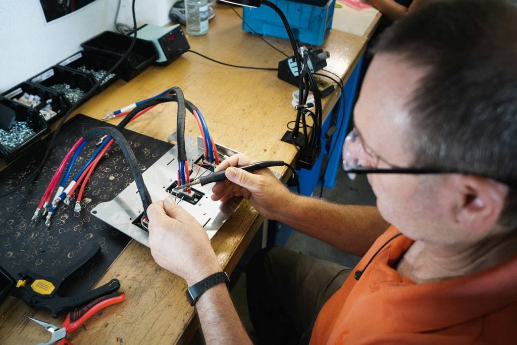 Man in orange shirt holding a hand tool