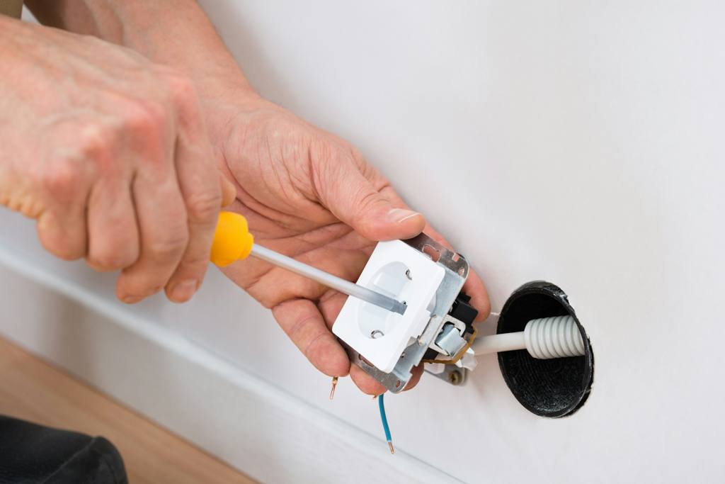 Technician fixing a wall outlet