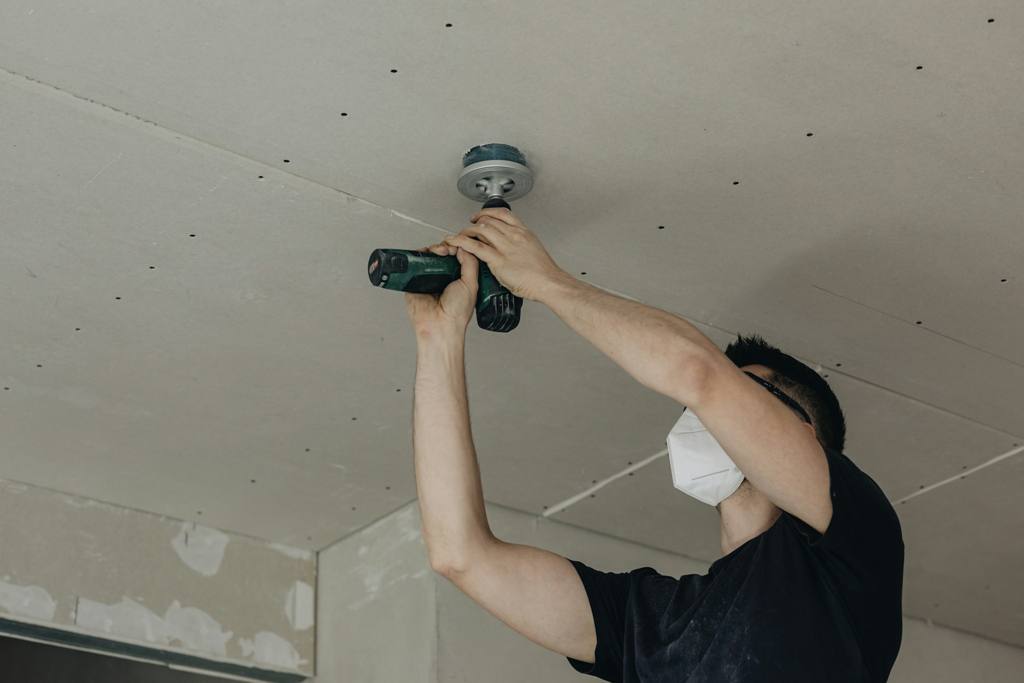 Person drilling a hole on the ceiling