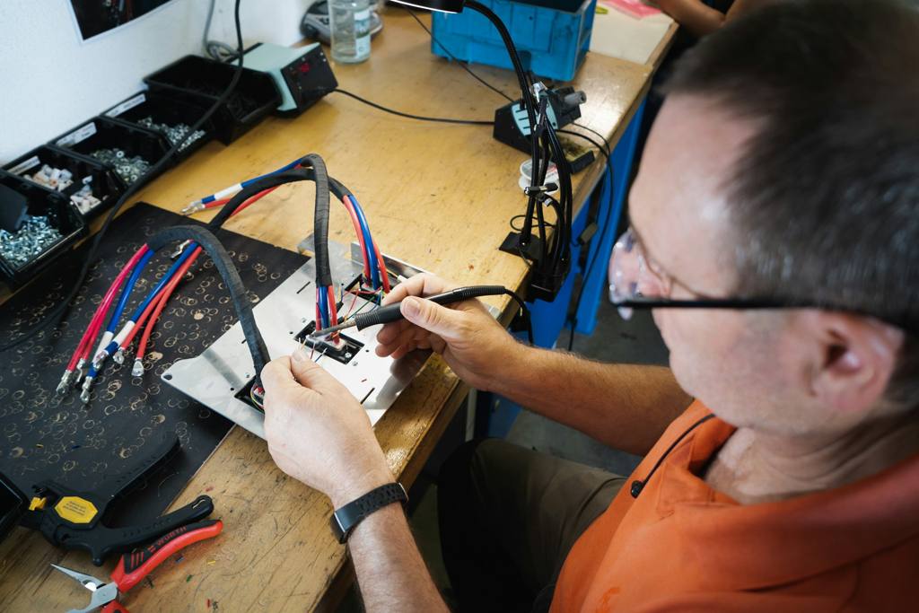 Man in orange shirt holding a hand tool