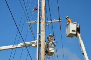 Two linemen working on an electric post