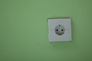 A white electrical outlet on a green wall