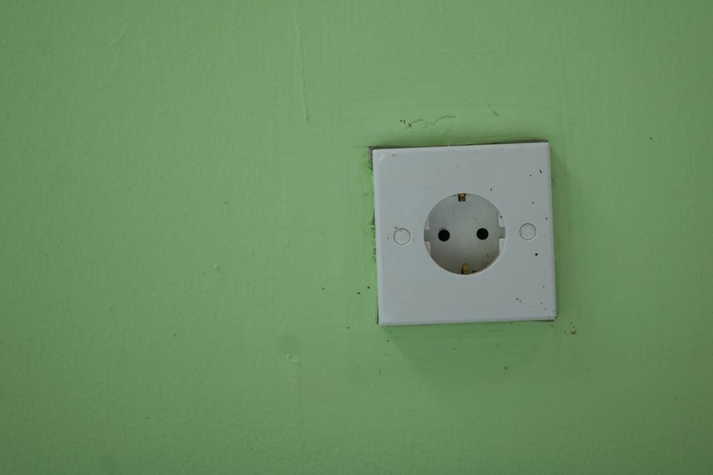 A white electrical outlet on a green wall